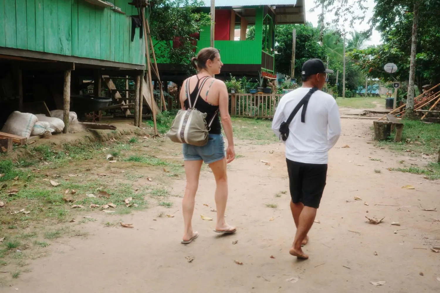 A traveler walking with a local guide through an Amazon river community