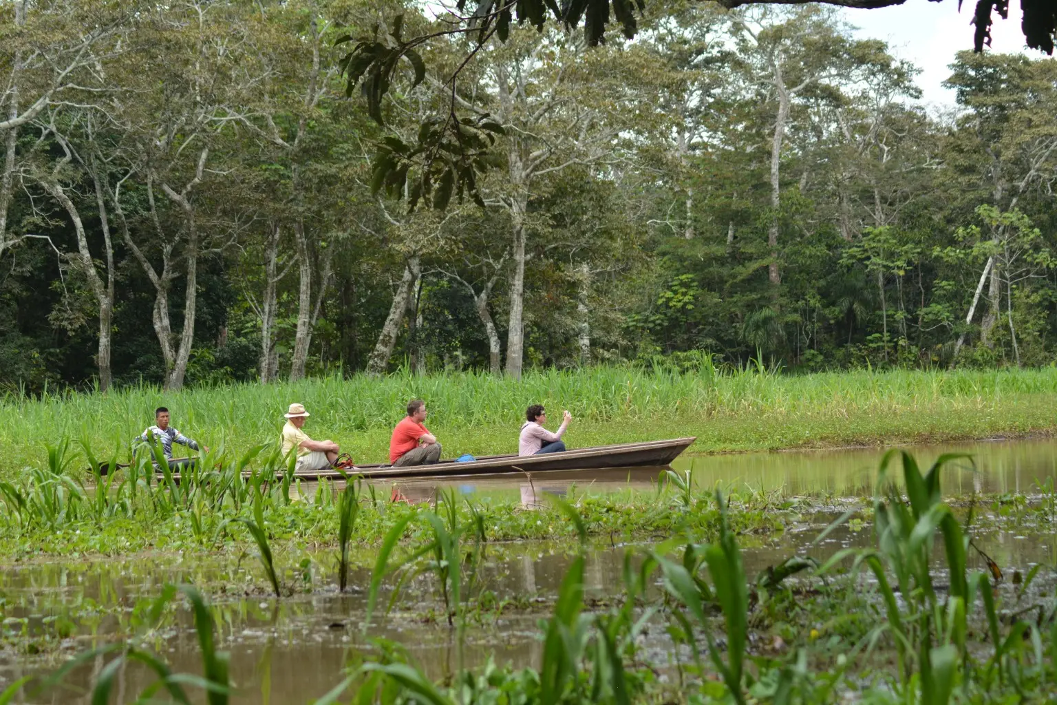 Travelers and a local guide moving by canoe through the Amazon forest