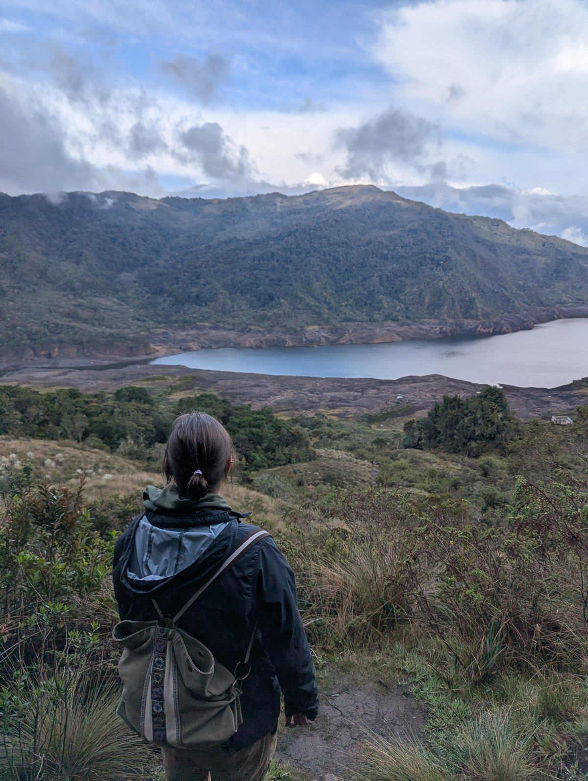 A traveler pauses above a high-altitude lake in the Andes