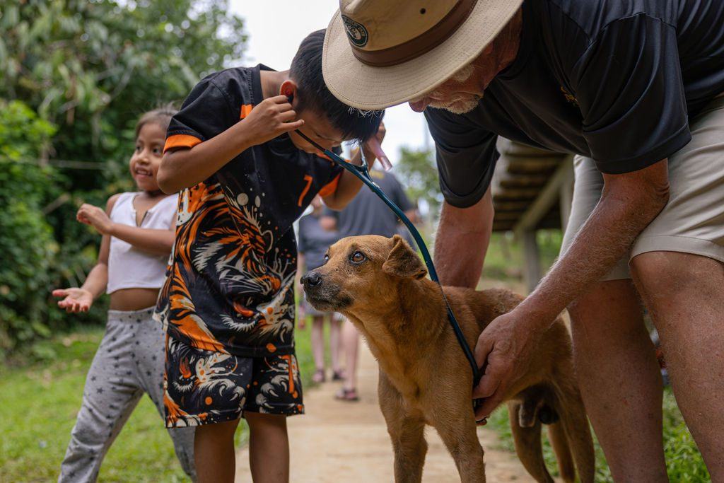 A young community member listens to a dog's heartbeat during veterinary outreach