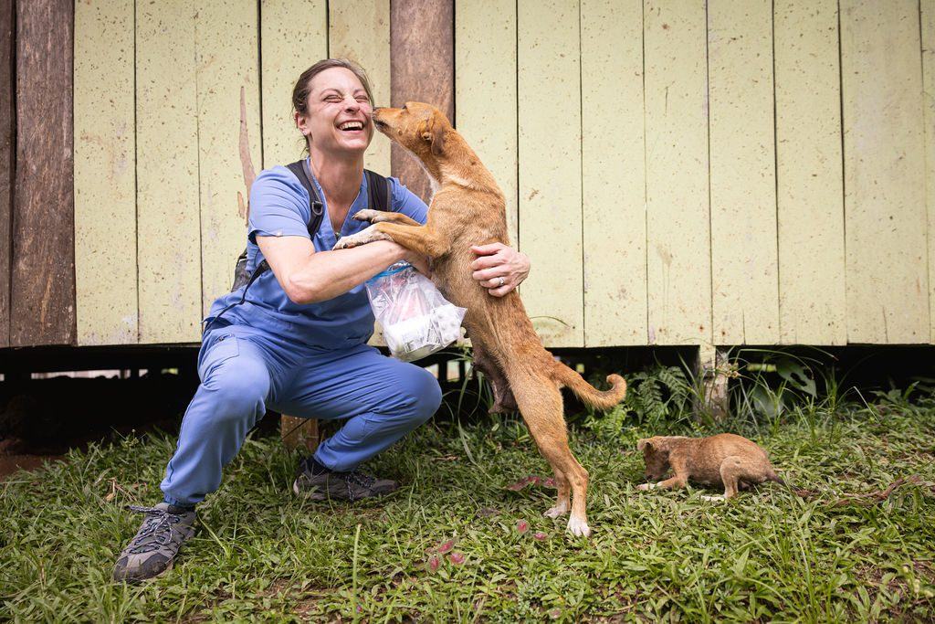 A rescue dog greets a veterinary volunteer during community outreach